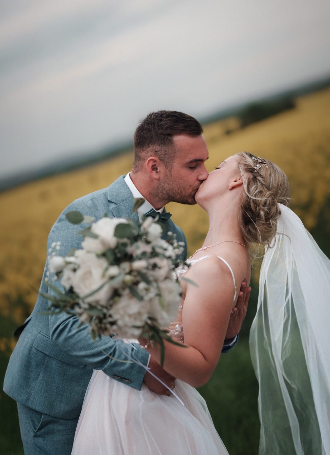 Brautpaar mit Strauß Brautpaar, das sich umarmt, mit einem Blumenstrauß und liebevollem Blick zueinander.